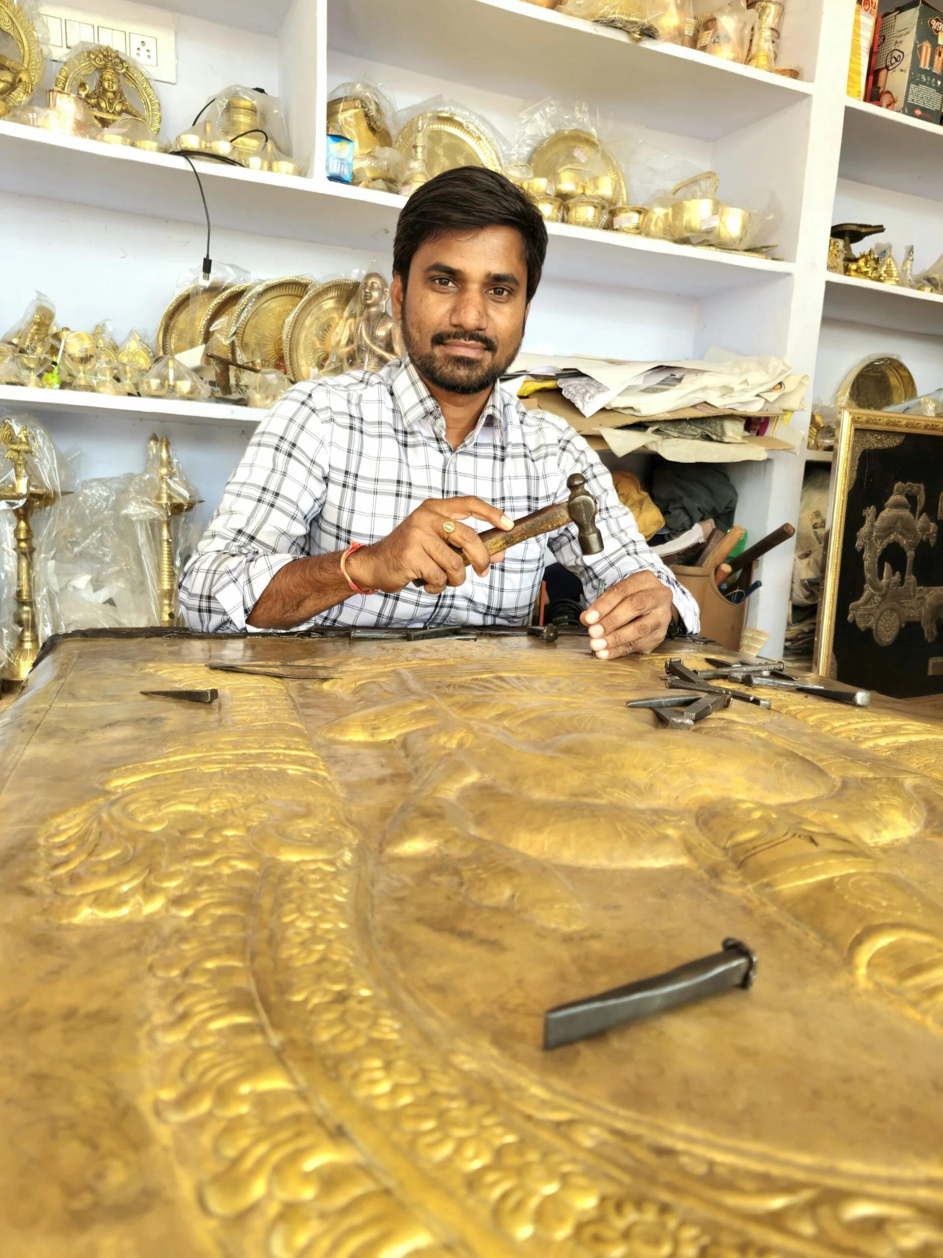 Artisan engraving detail into a brass surface
