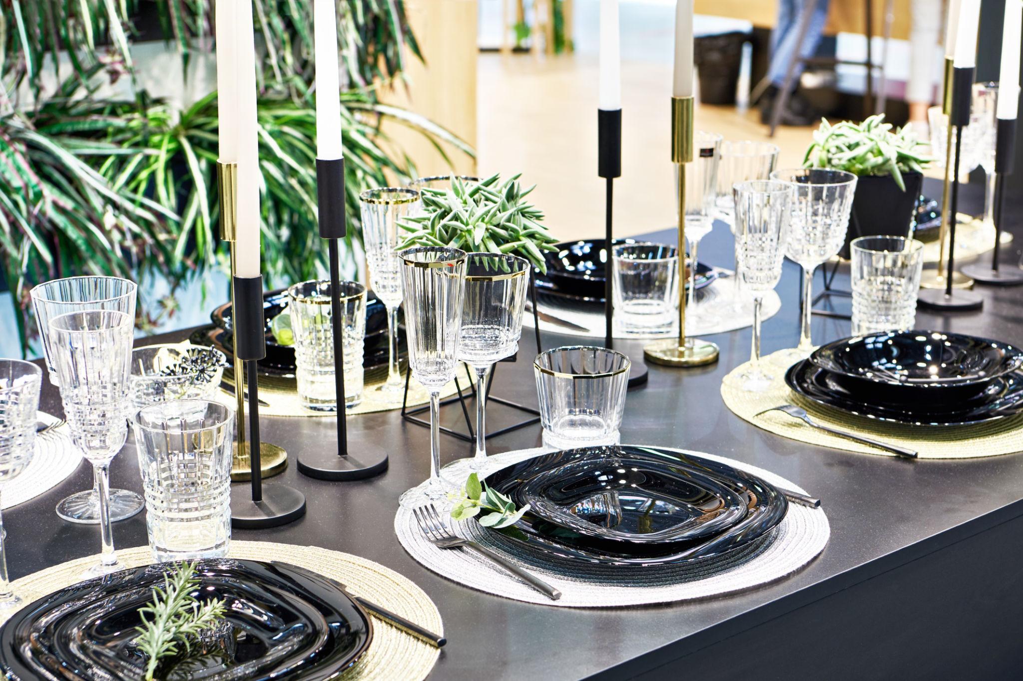 Dark festive table setting with candles and gold-rimmed plates